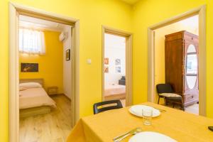 Habitación amarilla con mesa y dormitorio en Folklore House in Historical Catania - Happy Rentals, en Catania