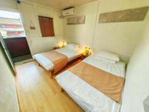 Habitación pequeña con 2 camas y ventana en Tulou Fuyulou Changdi Inn en Yongding