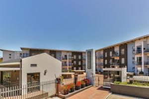 una fila de edificios de apartamentos con flores en un patio en WINK Aparthotel Quiver Tree, en Stellenbosch