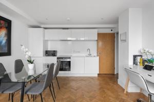 cocina y comedor con mesa de cristal y sillas en Parkway House en Chelmsford