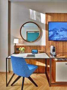 a desk with a blue chair and a mirror at EST Grand Hotel Savoy in Budapest
