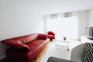 a living room with a red leather couch and a table at Haus Montanara in Unterbäch