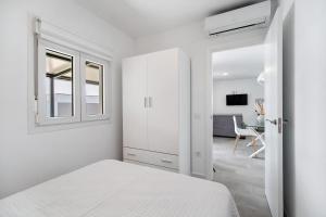 a white bedroom with a bed and a table at Dafer Piscina Privada in Chiclana de la Frontera