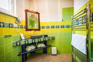 a green and yellow bathroom with a sink and a mirror at Penta Apartments in Gamlitz
