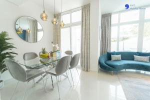 a living room with a blue couch and a glass table at AWS Homes - Elegant Villa with BBQ Area & Garden in Dubai