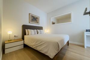 a bedroom with a large white bed and a night stand at Barcelona Amelie Apartment in Hospitalet de Llobregat