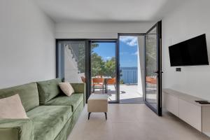 Una sala de estar con un sofá verde y un televisor. en Villa LiTo - only 50m from sea! - Makarska Exklusiv, en Brela