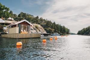 une maison sur l'eau avec des ballons orange dans l'eau dans l'établissement Lagunen Cottages and Hostel, à Strömstad