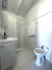 a white bathroom with a sink and a toilet at Aldiva Chalet in Torvaianica