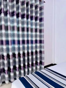 um quarto com uma cortina de duche listrada ao lado de uma cama em Geethani Tourist Home Polonnaruwa em Pollonaruva