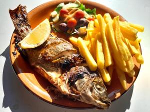 Crocodile Pools Resort في غابورون: صحن من الطعام مع سمك وبطاطس مقلية
