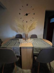 a dining room table with a clock on the wall at My Sweet Home in Tríkala