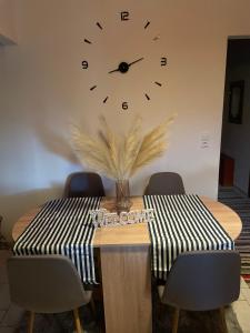 a dining room table with a clock on the wall at My Sweet Home in Tríkala