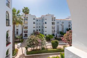 an apartment building with trees and flowers in a courtyard at Manilva Home in San Luis de Sabinillas