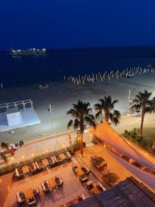 a view of a beach at night with chairs and palm trees at Angel Beach Hotel Kızkalesi Mersin in Erdemli