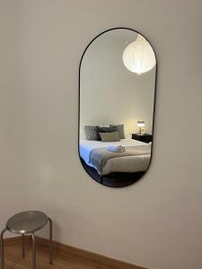 een spiegel in een kamer met een bed en een kruk bij Plaza España 238 in Barcelona