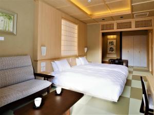 a bedroom with a large white bed and a chair at Hotel Morinokaze Hakone Sengokuhara in Hakone