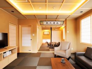 a living room with a couch and a tv at Hotel Morinokaze Hakone Sengokuhara in Hakone