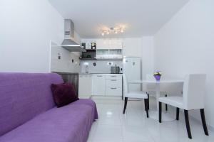 a living room with a purple couch and a kitchen at Apartment Ema in Dubrovnik