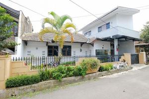 a white house with a palm tree in front of it at Wisma 812 Khusus Putra for Male Only in Bandung