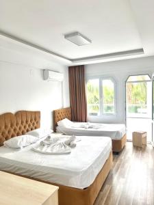 two beds in a room with two windows at Angel Beach Hotel Kızkalesi Mersin in Erdemli