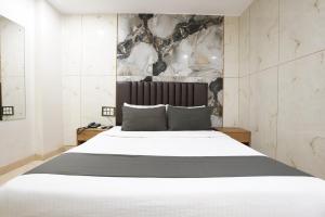 a bedroom with a white bed with a black headboard at Hotel U Life Residency Mumbai in Mumbai