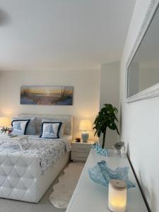 a white bedroom with a bed and a table at Ferienwohnung Strandoase inklusive Terrasse und Parkplatz - Sonnenseite in Scharbeutz +11 photos