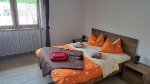 Una cama con almohadas naranjas y una bolsa roja. en Pensiunea Inima Daciei en Costeşti