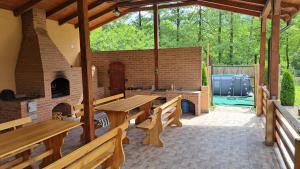a patio with wooden benches and a brick fireplace at Pensiunea Inima Daciei in Costeşti