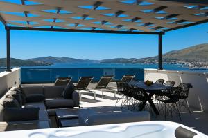 patio con sedie, tavolo e vista sull'acqua di Penthouse Bluesky a Okrug Gornji