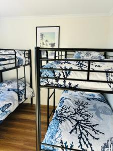 Habitación con 3 literas y sábanas azules y blancas. en Nellies Hideaway 1-20 Troon Drive, en Normanville