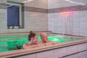 dos personas en una piscina con una fuente en Royal Club Hotel, en Visegrád