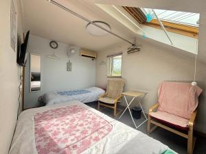 a room with two beds and two chairs in it at Guest House モモ in Obihiro