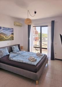 a bedroom with a bed and a large window at Sea Vacation Homes in Chernomorets