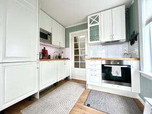 een keuken met witte kasten en een fornuis bij Sentrum - Koselig hus med parkering in Arendal