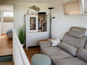 Prima Resort Boddenblick - Camping & Tiny House-Resort في Groß Kordshagen: غرفة معيشة مع أريكة ورف كتاب