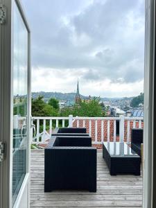 a balcony with chairs and tables and a view of a city at Sentrum - Koselig hus med parkering in Arendal