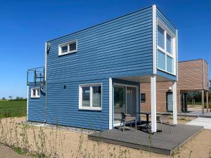 Prima Resort Boddenblick - Camping & Tiny House-Resort في Groß Kordshagen: منزل أزرق على طاولة وكراسي على السطح