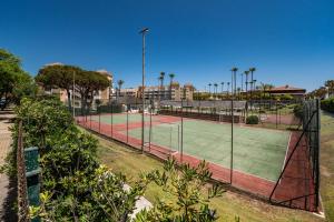 twee tennisbanen met palmbomen en gebouwen bij Kiko Las Americas in Isla Cristina