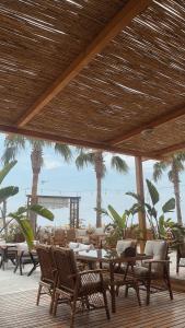 un patio con mesas, sillas y palmeras en Angel Beach Hotel Kızkalesi Mersin, en Erdemli
