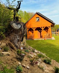 una cabaña de madera con un tronco de árbol delante de ella en Chatka Dziadka Sudety en Stary Gieraltow