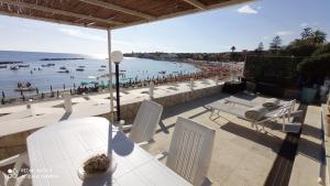 a group of white tables and chairs on a beach at Villa con Piscina Privata fronte Spiaggia in Santa Marinella