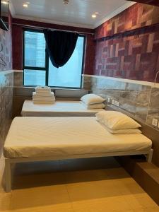 3 camas en una habitación con ventana en Venetian Hostel, en Hong Kong