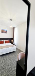 1 dormitorio con cama, escritorio y espejo en Evelia Hotels, en Niza