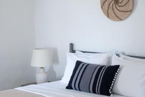 una camera da letto con un letto con cuscini bianchi e una lampada di Spiti Apartment a Mylopotas