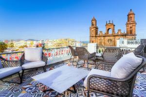 a group of chairs and tables on a balcony with a building at Boutique Hotel Cordial Plaza Mayor de Santa Ana in Las Palmas de Gran Canaria