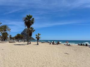 personas en una playa con palmeras y el océano en Playa de Oro 14C, en Calpe