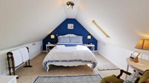 - une chambre bleue et blanche avec un lit dans le grenier dans l'établissement Keep Cottage - East Devon, à Southleigh