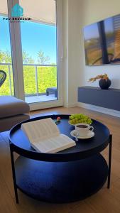 a coffee table with a book and a bowl of fruit at Pod Brzozami Apartamenty Gąski in Gąski