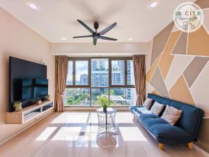 uma sala de estar com um sofá azul e uma televisão de ecrã plano em Iskandar Residence by JBcity Home em Nusajaya